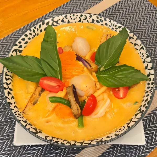 Thai Diva Cuisine's yellow curry with lychee, tomatoes, and basil in a decorative bowl.