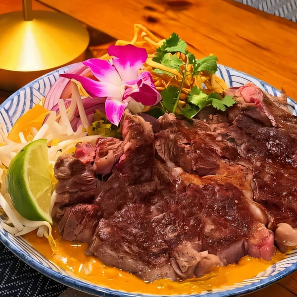 Thai Diva Cuisine's beef dish with lime, red onion, cilantro, and a pink orchid garnish.